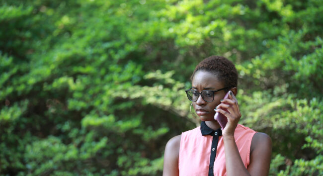 Young-contemporary-African-woman-looking-gloomy-and-upset-while-speaking-on-phone-in-park