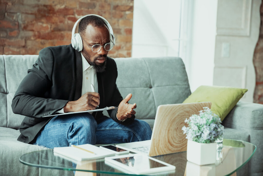 Man takes notes while on a video conference call at home