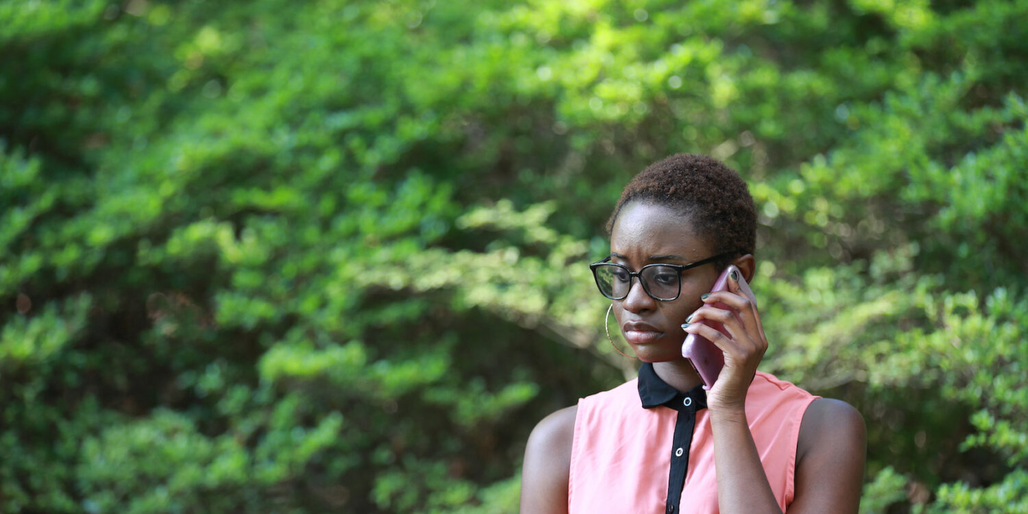 Young-contemporary-African-woman-looking-gloomy-and-upset-while-speaking-on-phone-in-park